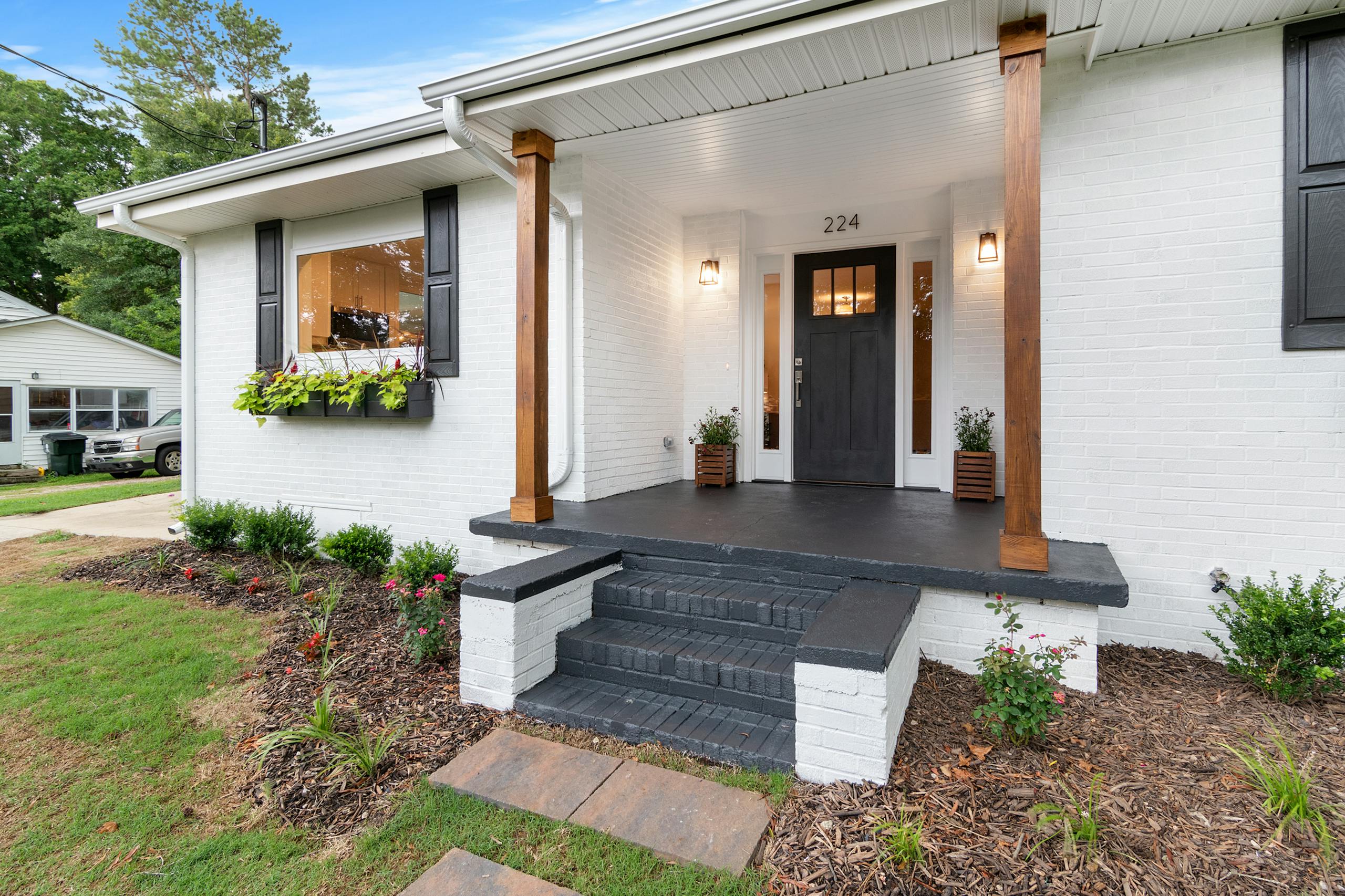 Front view of a charming white brick suburban house with black accents.